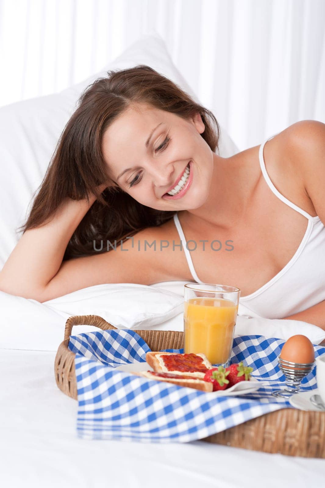 Happy woman in white bed having homemade breakfast