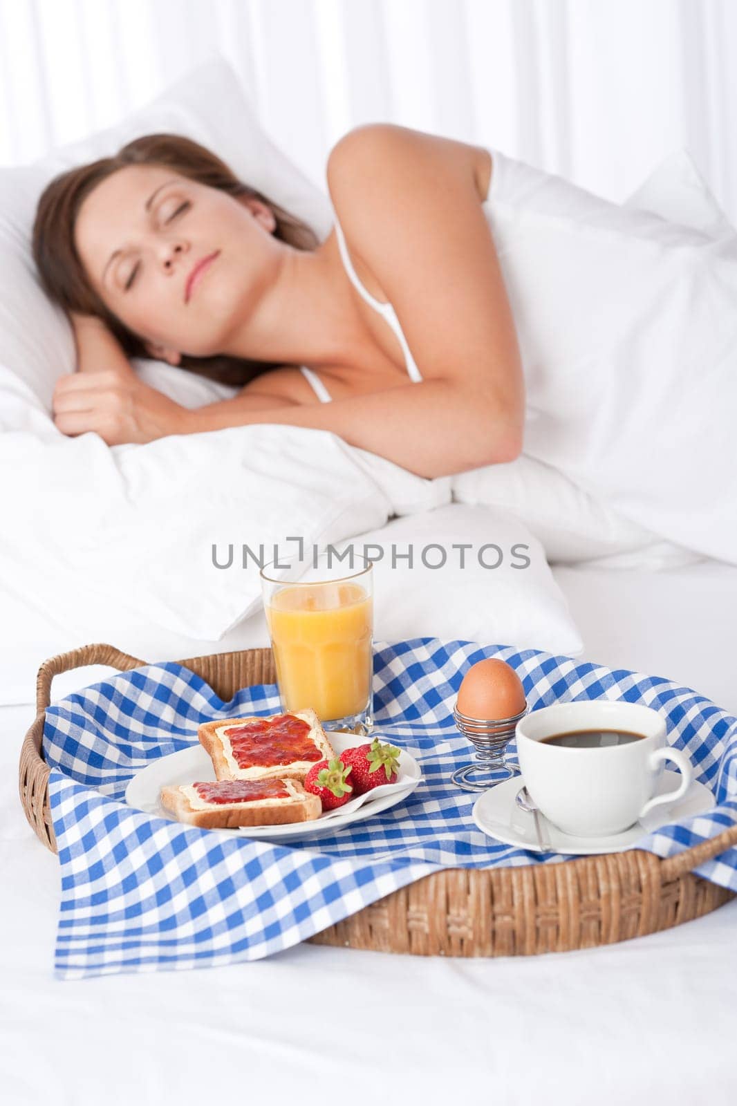 Woman sleeping in white bed, homemade breakfast in foreground