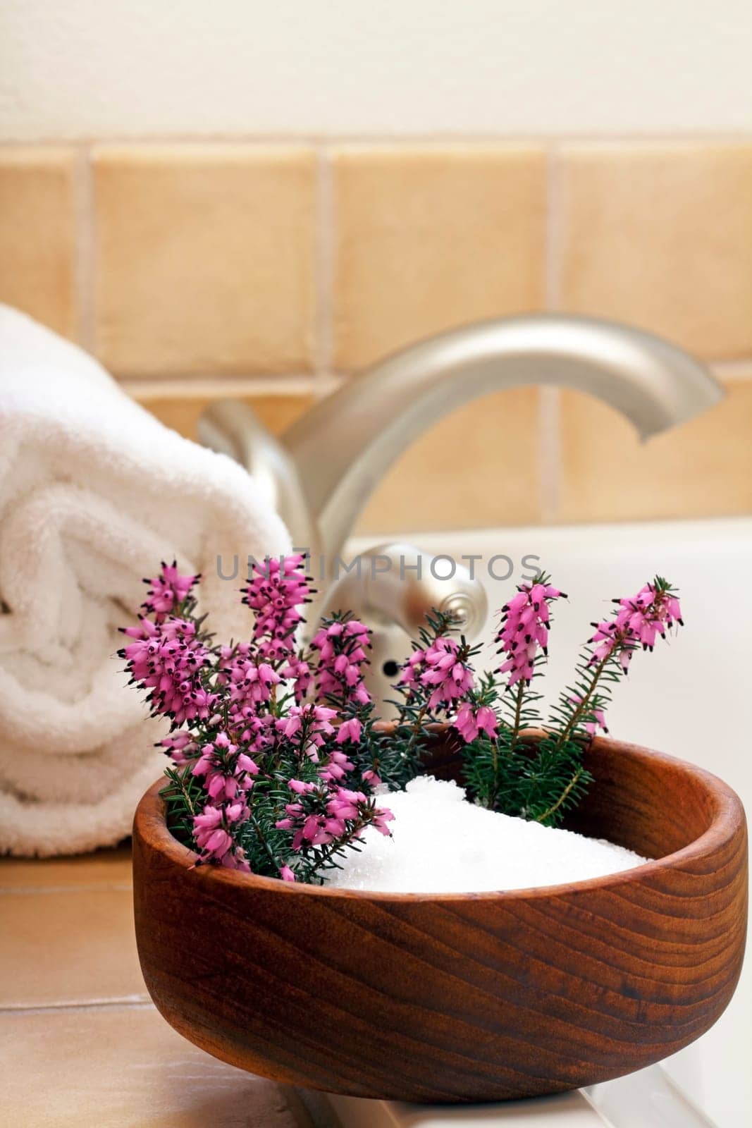 Pretty heather flowers in a bowl of Epsom salts on a bath tub edge ready to bathe.