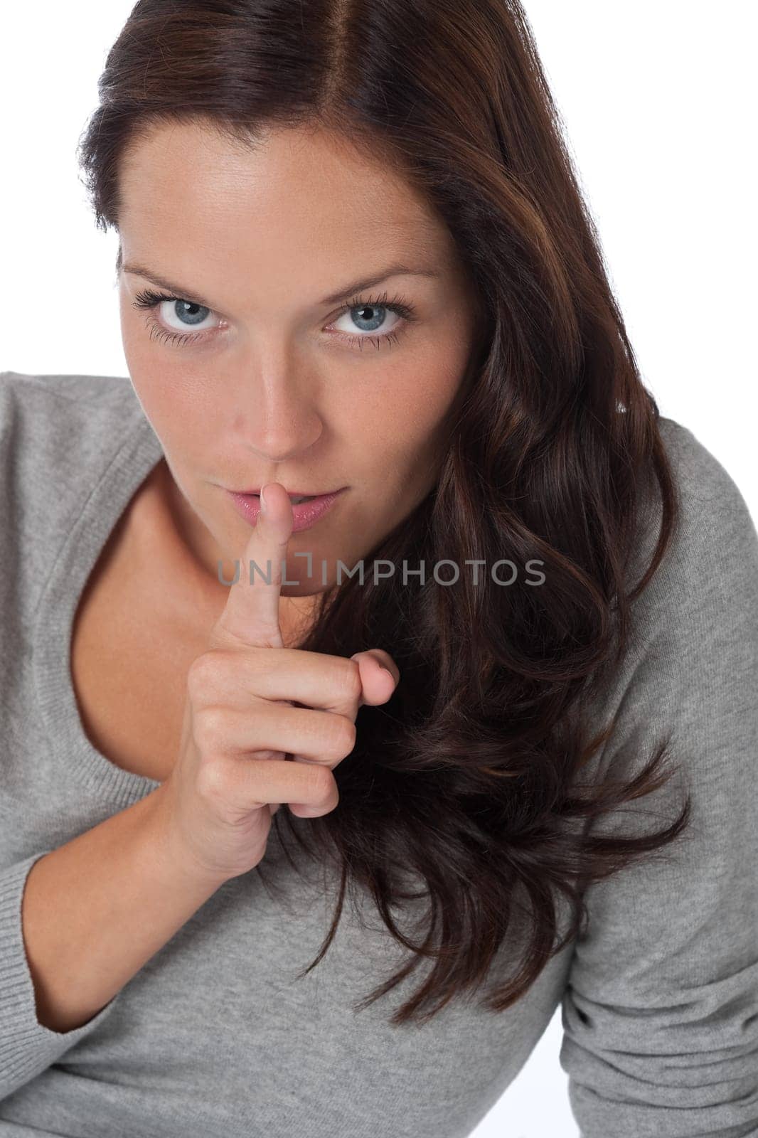 Beautiful woman expressing silence, finger on lips, on white background