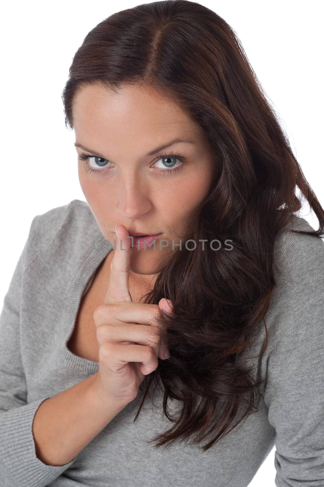 Beautiful woman expressing silence, finger on lips, on white background