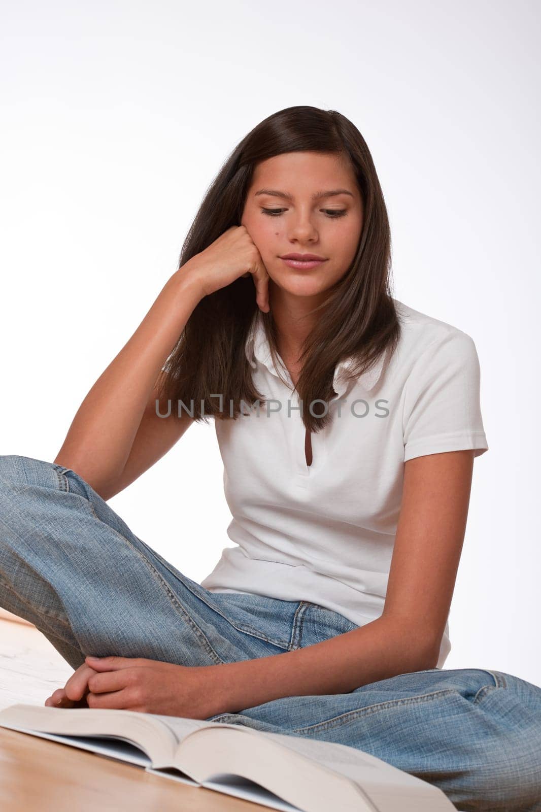 Happy teenager sitting with book on wooden floor