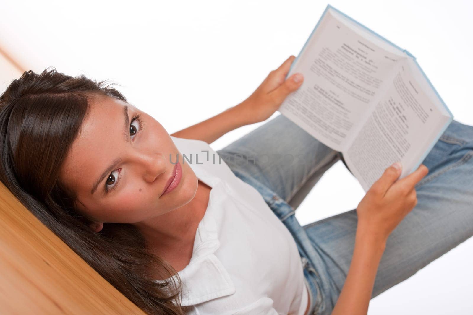 Brown hair teenager lying on wooden floor holding book