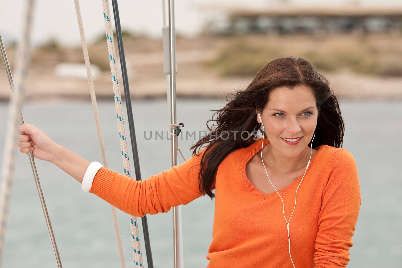 Attractive woman standing on sailing boat holding rope