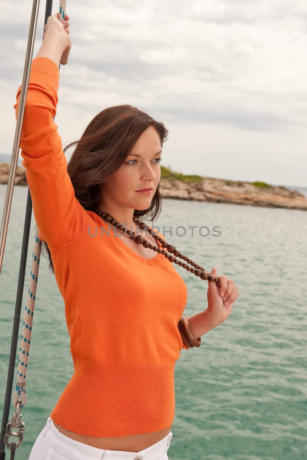 Attractive woman sailing on luxury yacht holding rope