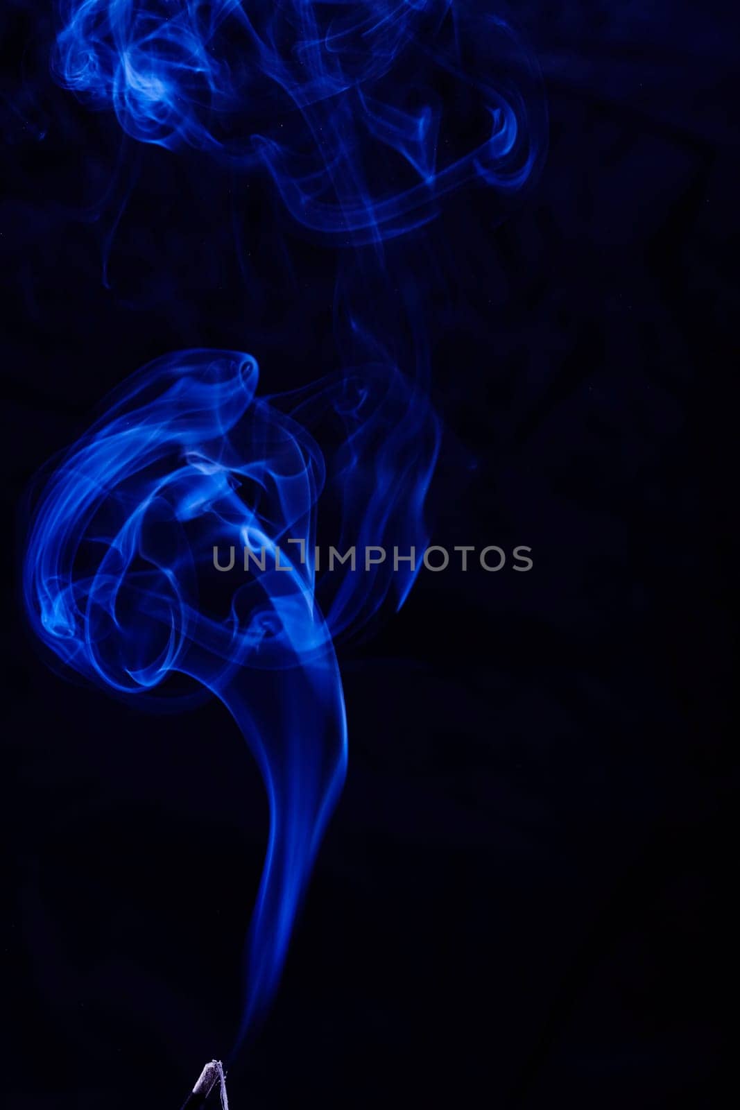 Abstract incense blue smoke against black background
