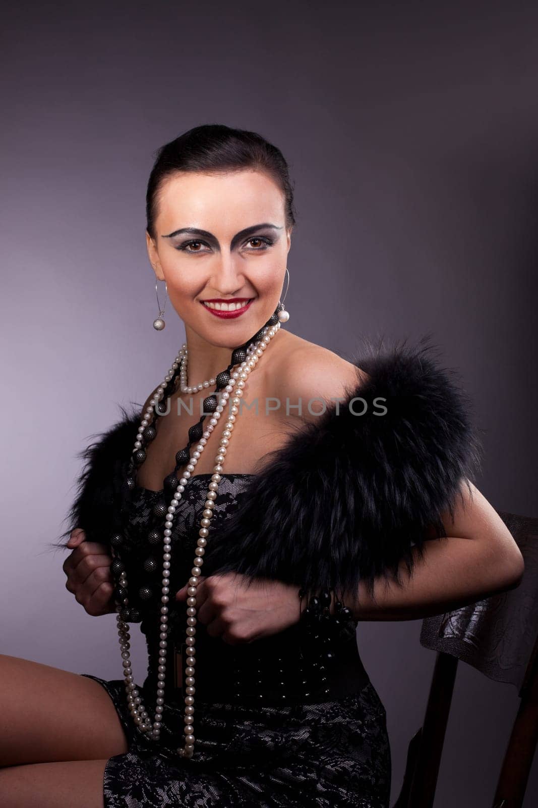 Proud woman smile in fur boa with pearl beads on chair