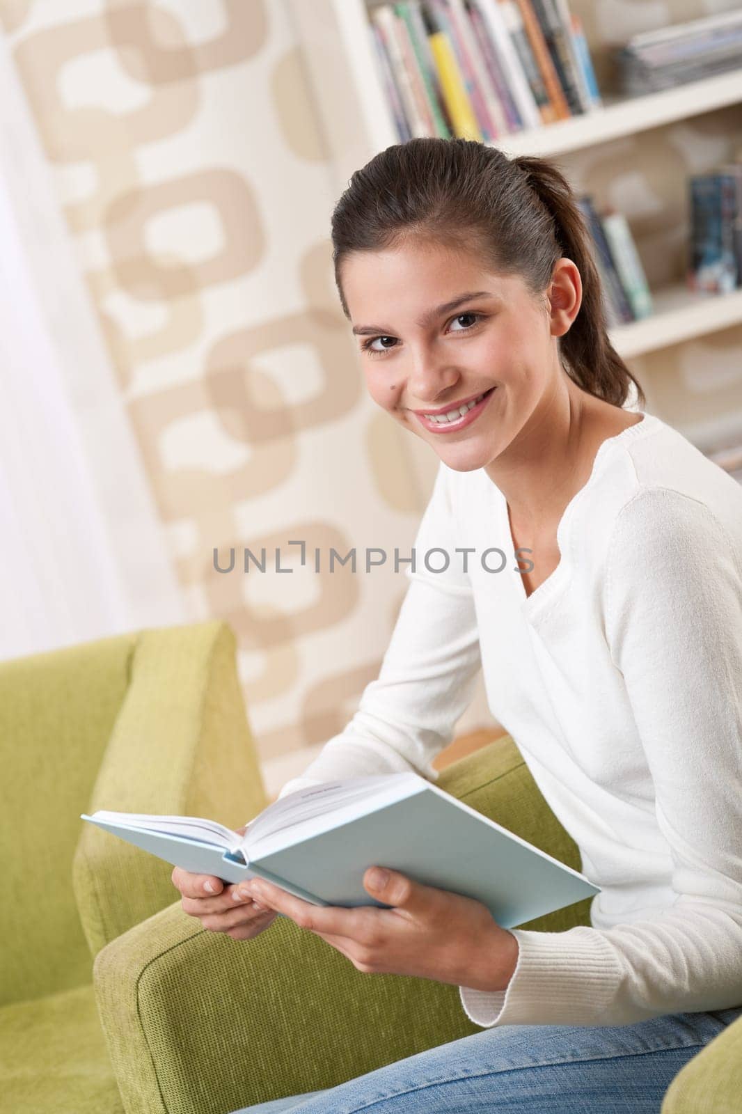 Students - Happy teenager with book sitting on armchair in lounge