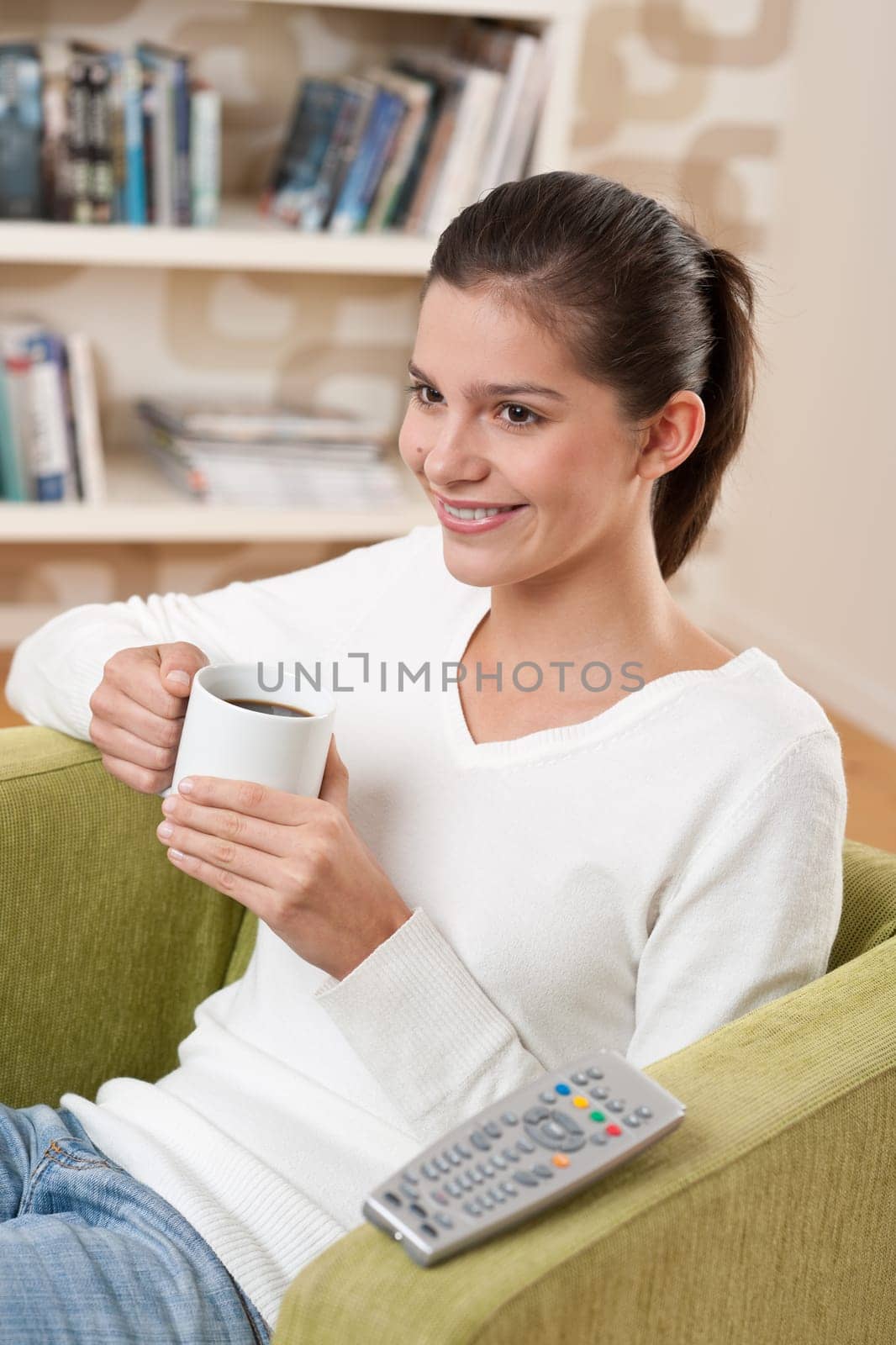 Students - Happy female teenager having drink watching television in living room