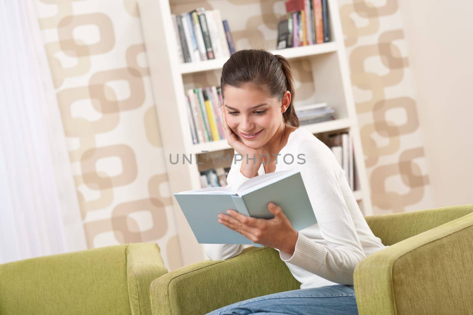 Students - Happy teenager with book sitting on armchair in lounge