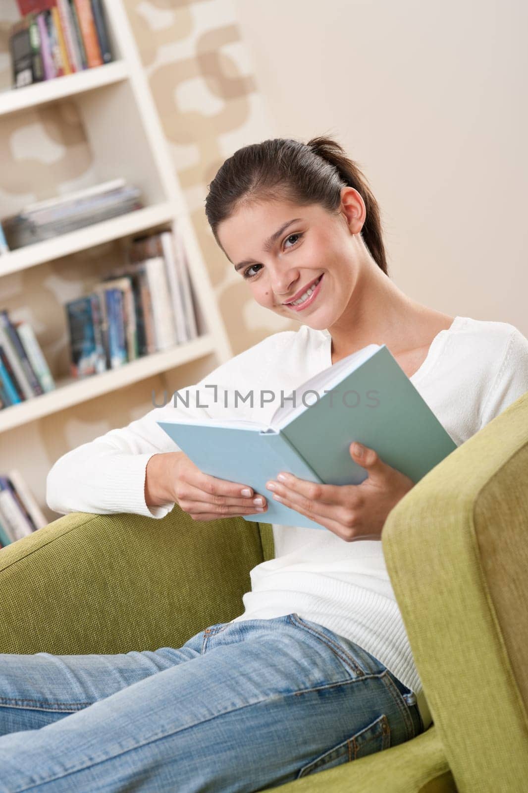 Students - Happy teenager with book sitting on armchair in lounge