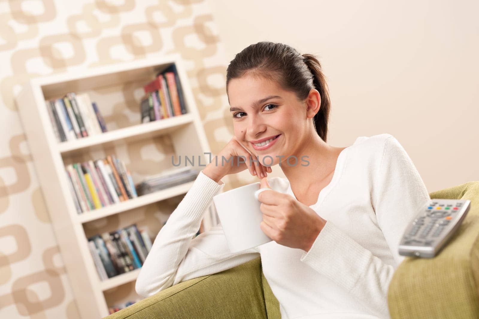 Students - Happy female teenager having drink watching television in living room