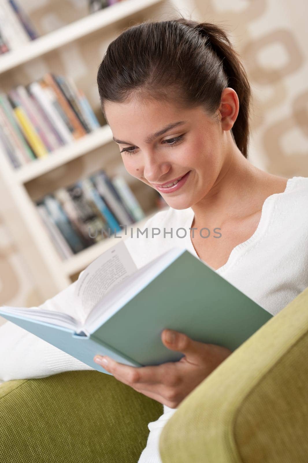 Students - Happy teenager with book sitting on armchair in lounge