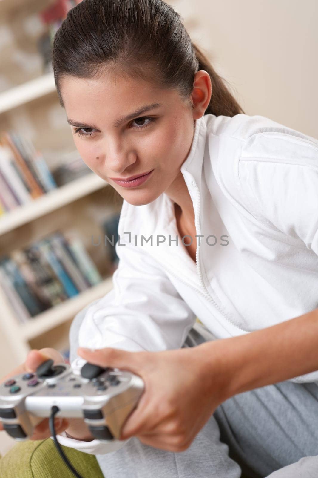 Students - Female teenager playing video game holding game pad in living room