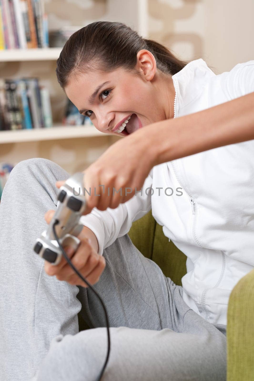 Students - Female teenager playing video game holding game pad in living room