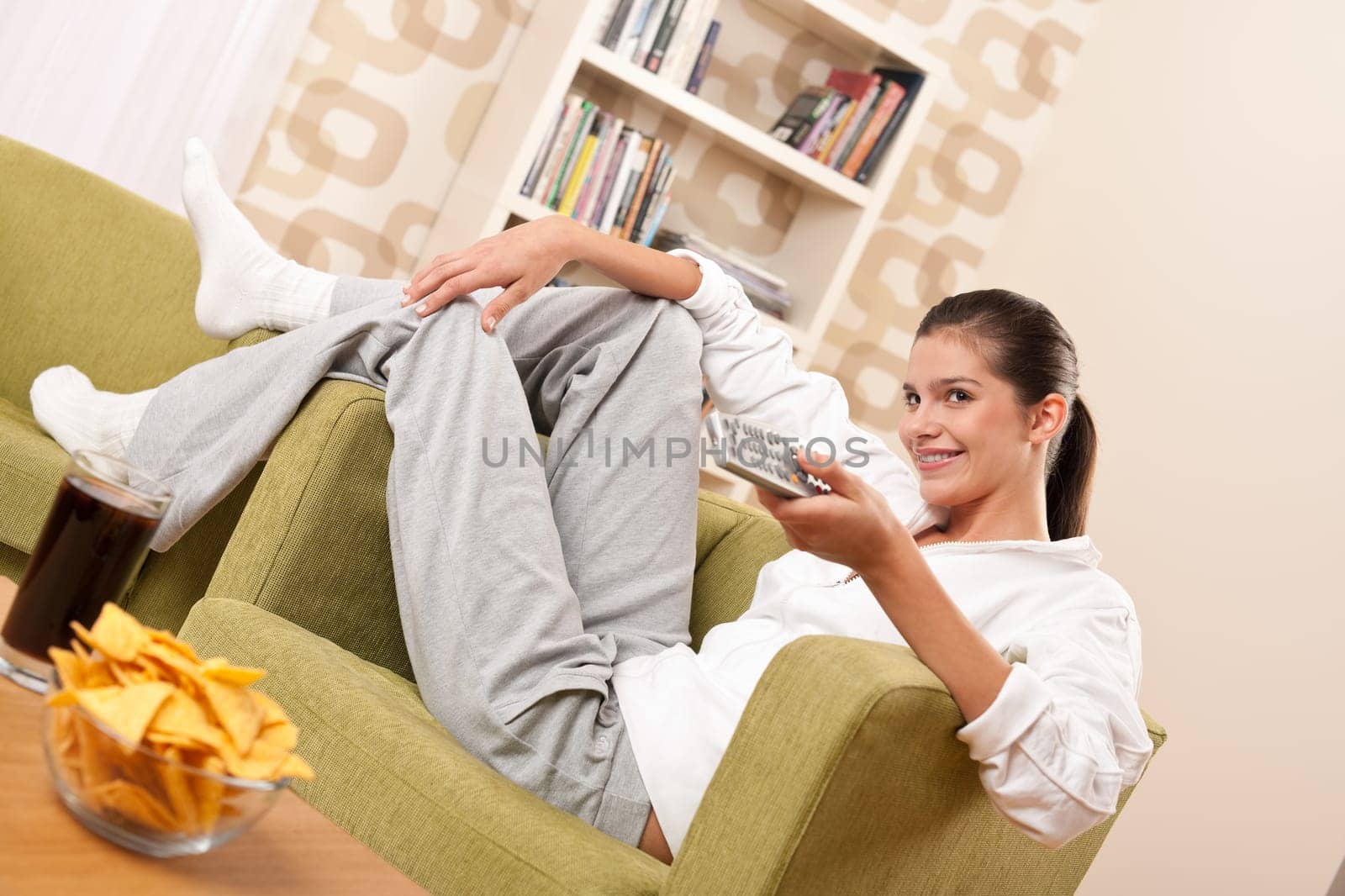 Students - Happy female teenager with potato chips in modern living room