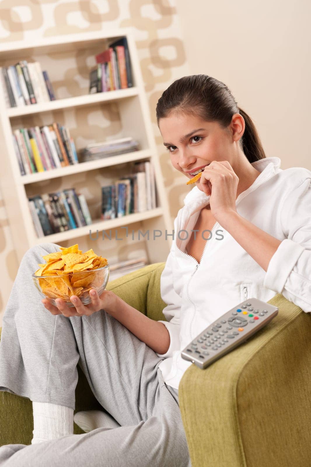 Students - Happy female teenager with potato chips in modern living room