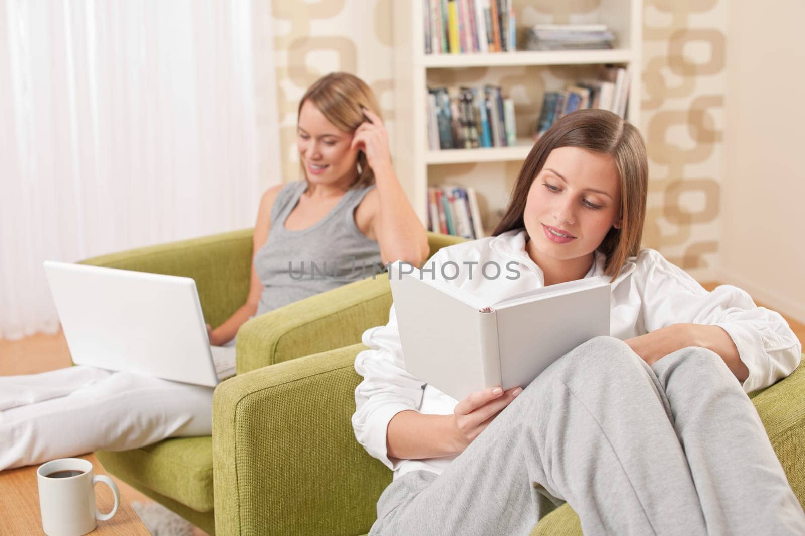 Students - Two female students studying in lounge, reading book
