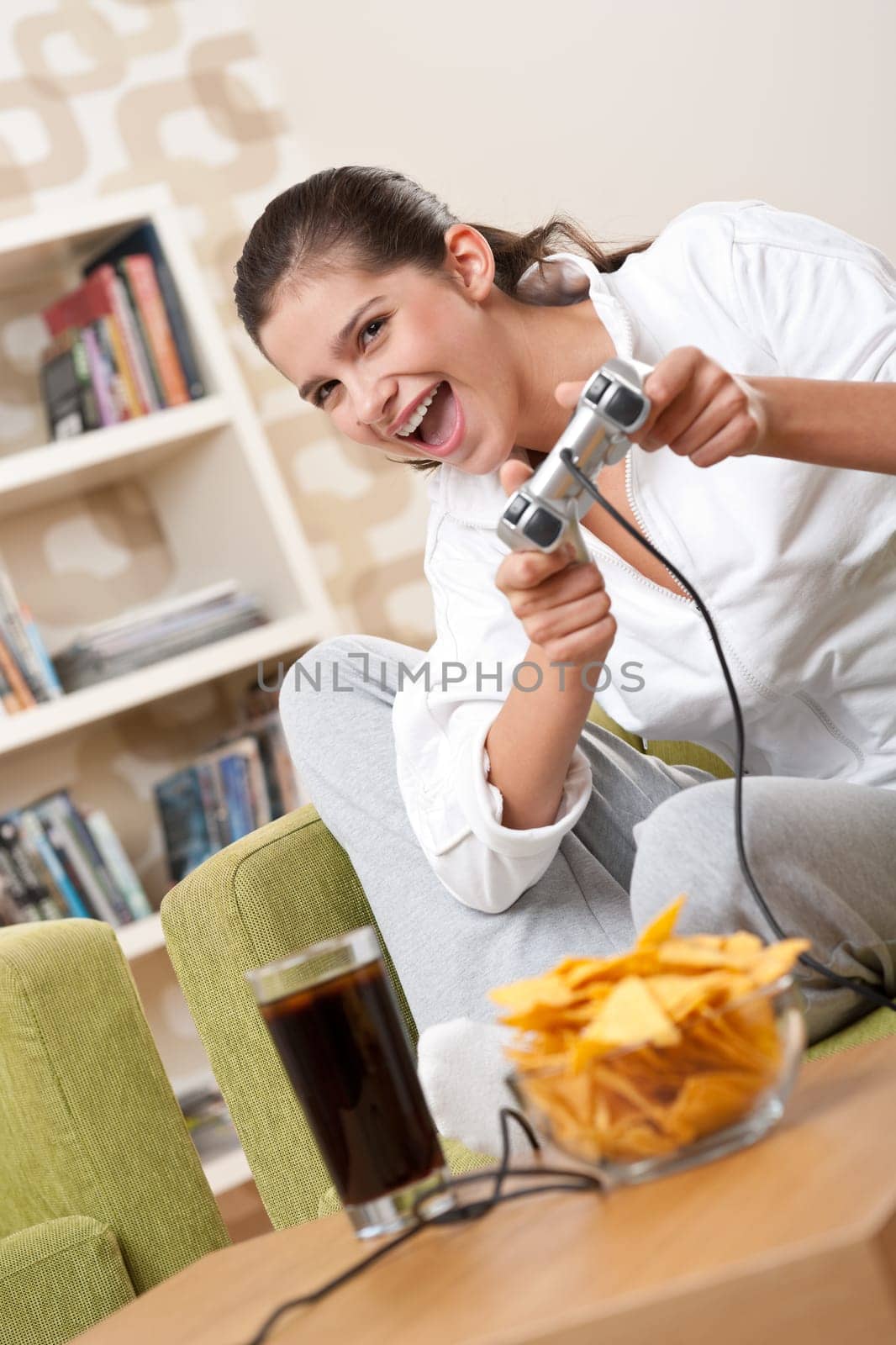 Students - Female teenager playing video game holding game pad in living room