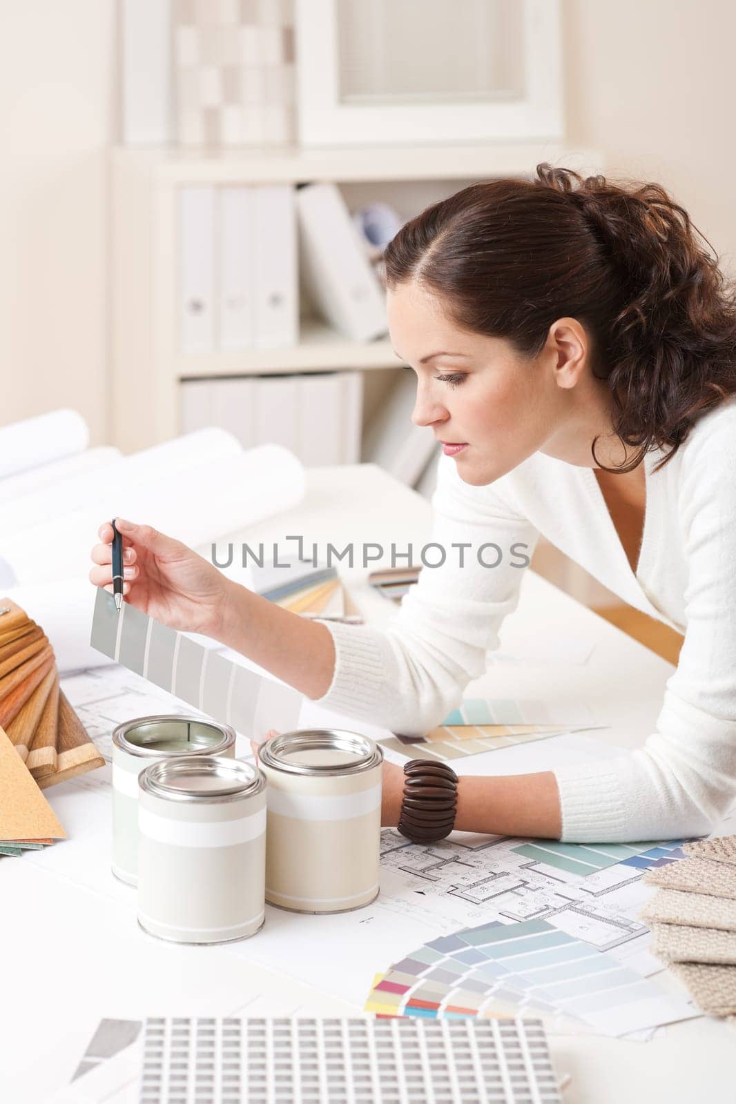 Young female interior designer at office with paint and color swatch