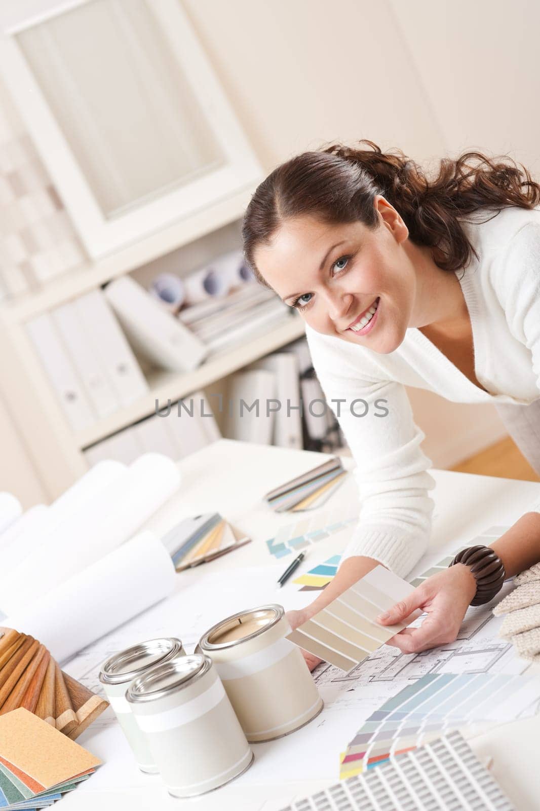 Young female interior designer at office with paint and color swatch