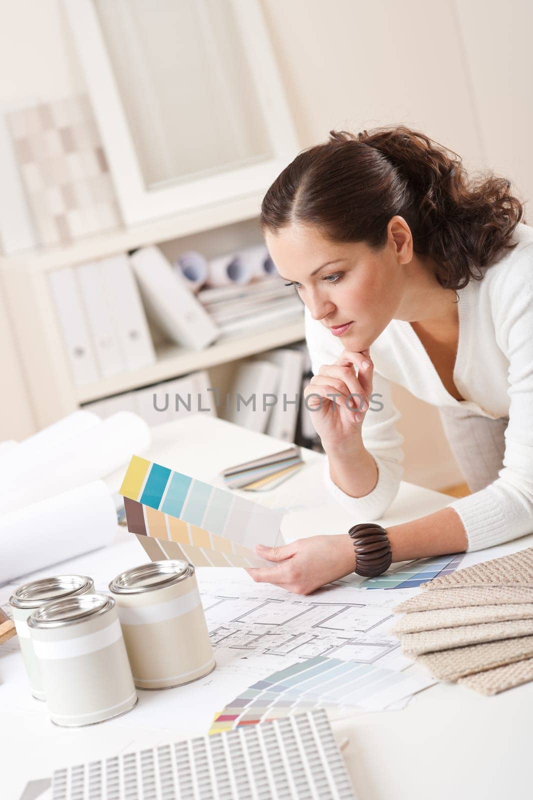 Young female interior designer at office with paint and color swatch
