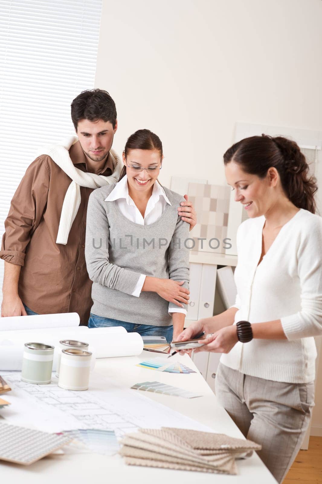 Female interior designer with two clients at office choosing colors