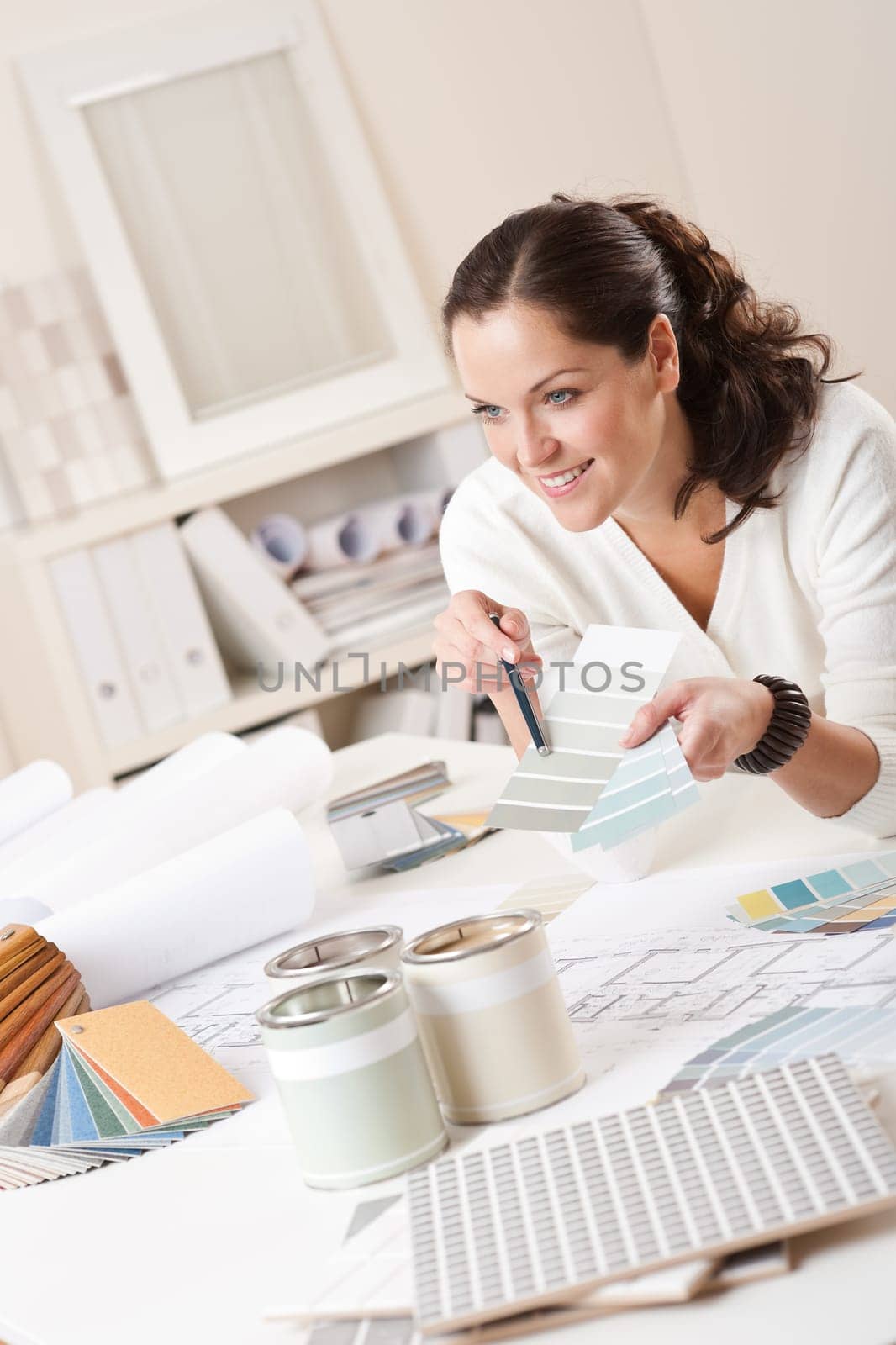 Female interior designer working at office with color swatch and paint