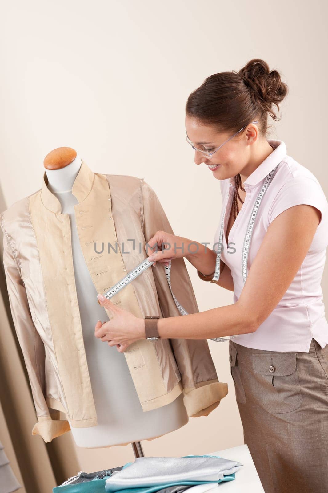 Female fashion designer taking measurement of jacket at studio