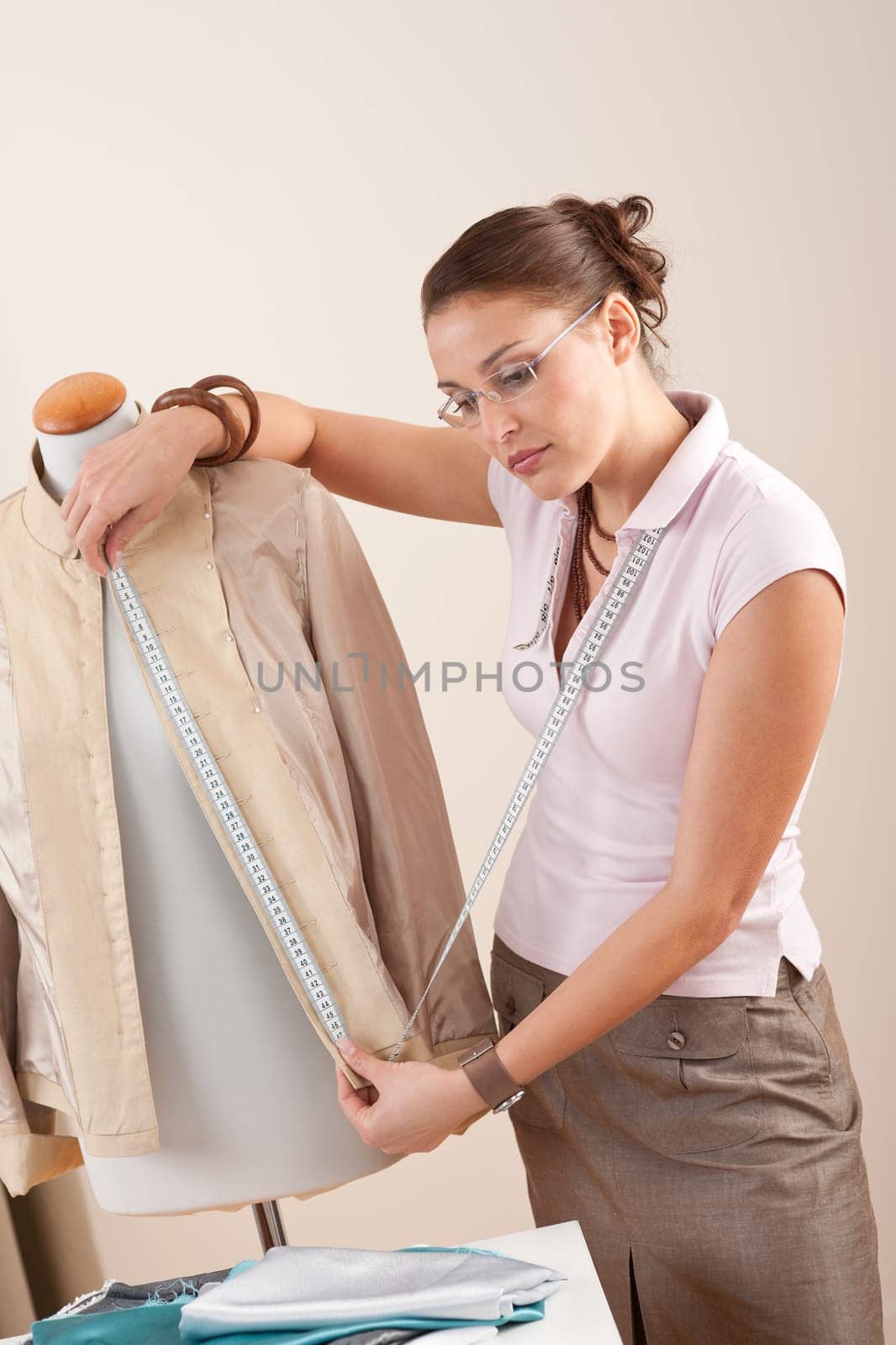 Female fashion designer taking measurement of jacket at studio