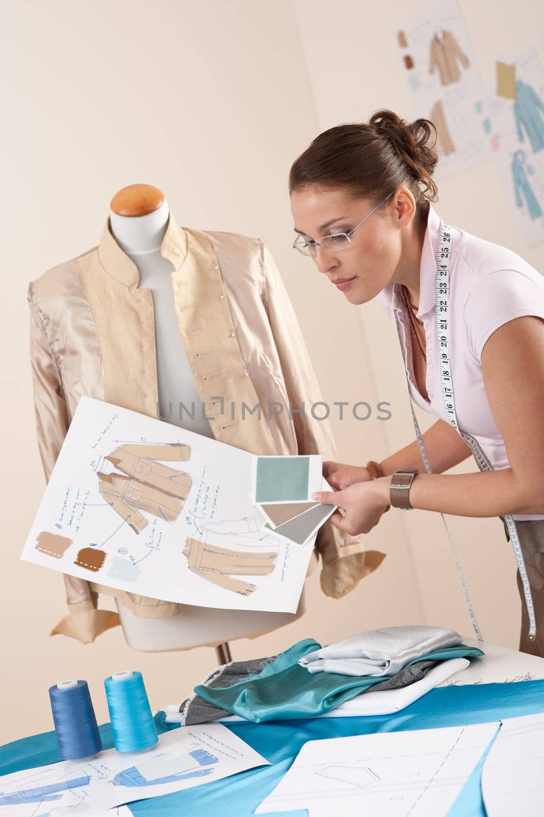 Female tailor working at fashion studio with mannequin