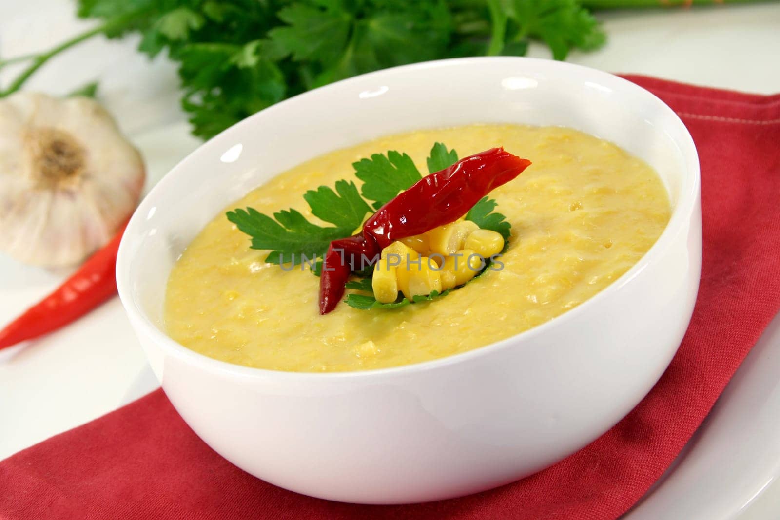 a bowl of corn soup with chili and parsley