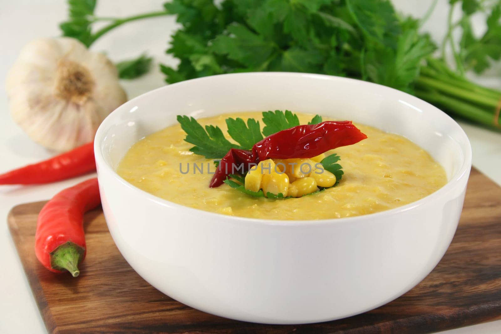 a bowl of corn soup with chili and parsley