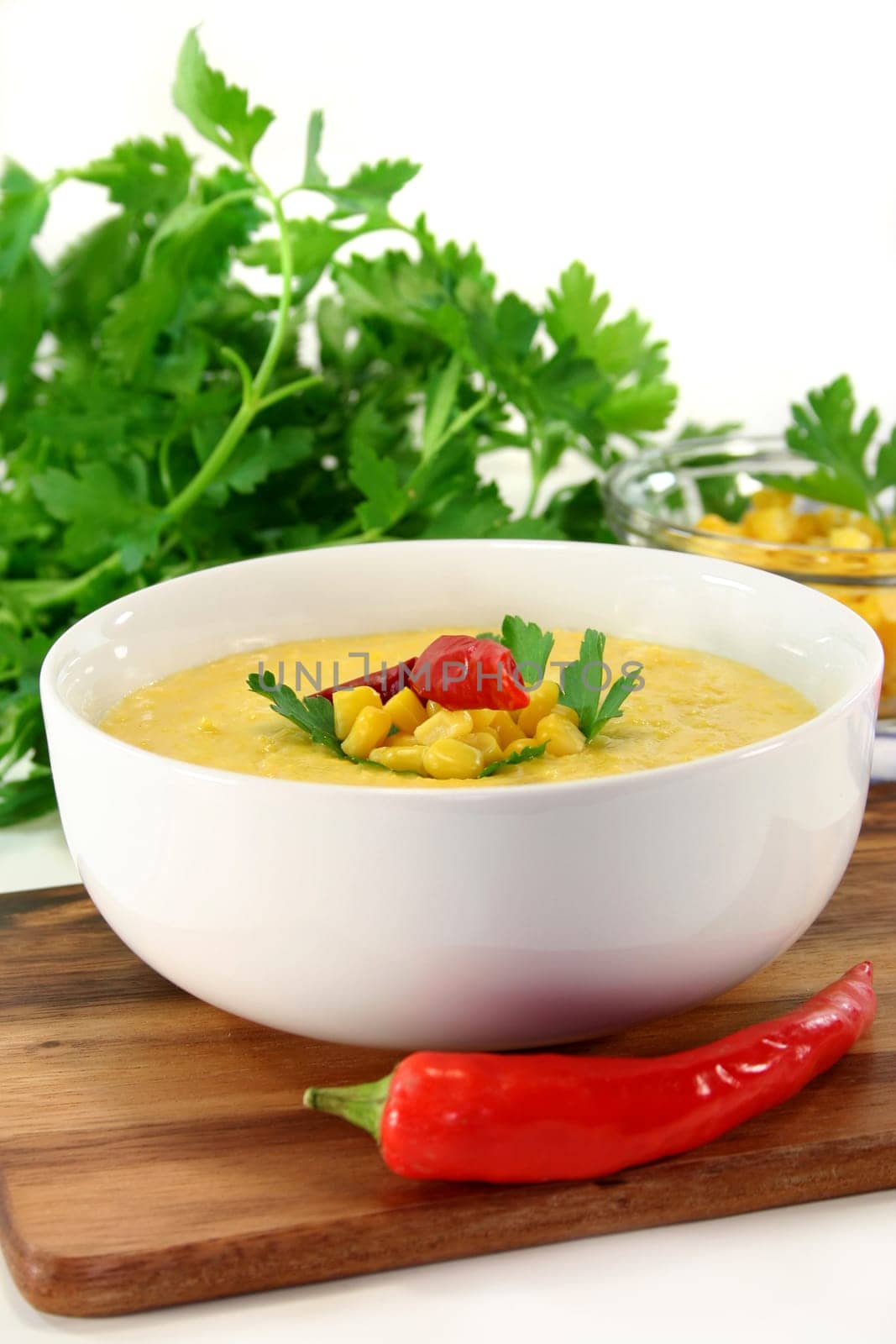 a bowl of corn soup with chili and parsley
