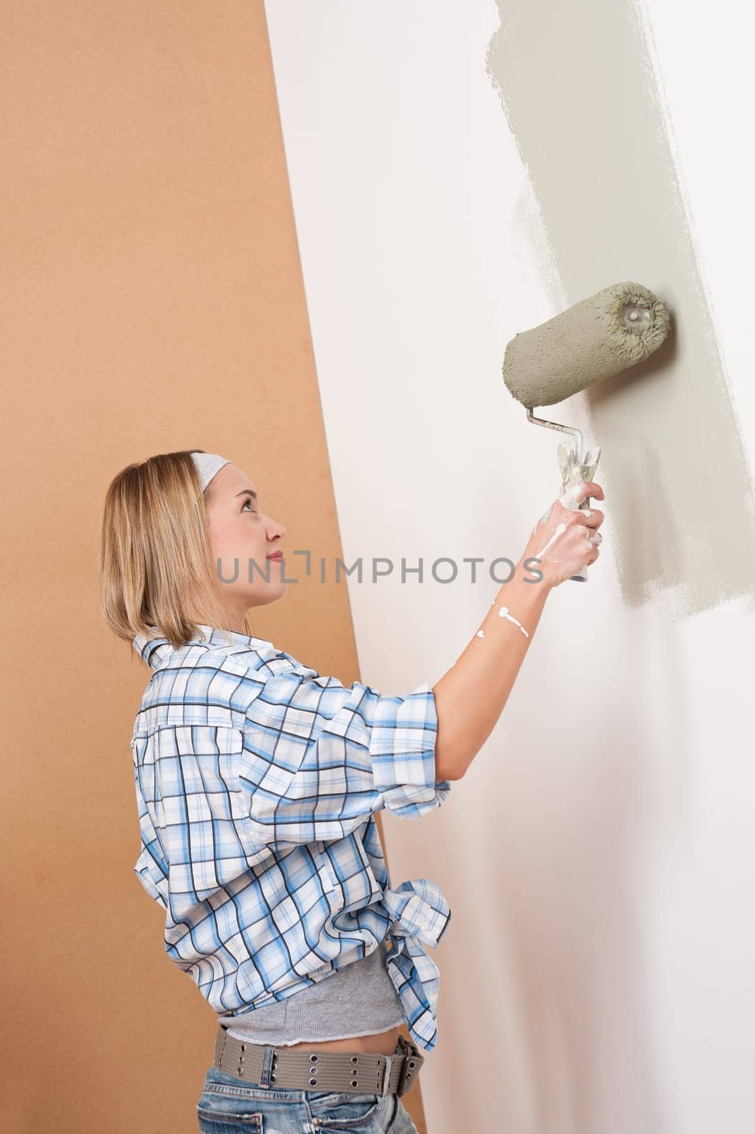Home improvement: Blond woman painting wall with paint roller