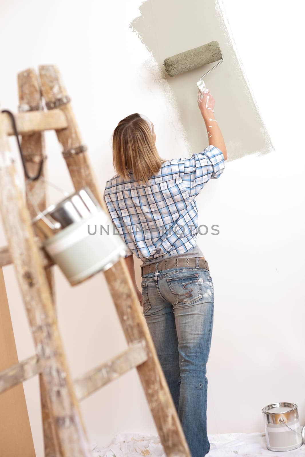 Home improvement: Blond woman painting wall with paint roller