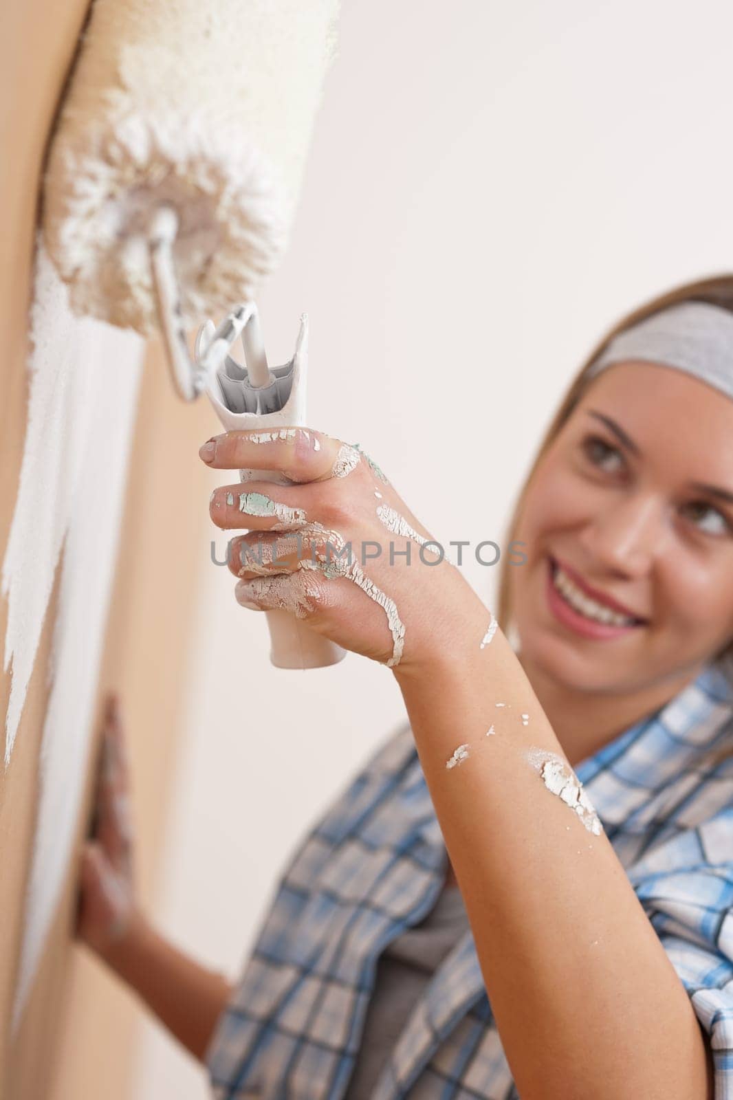 Home improvement: Young woman painting wall with paint roller