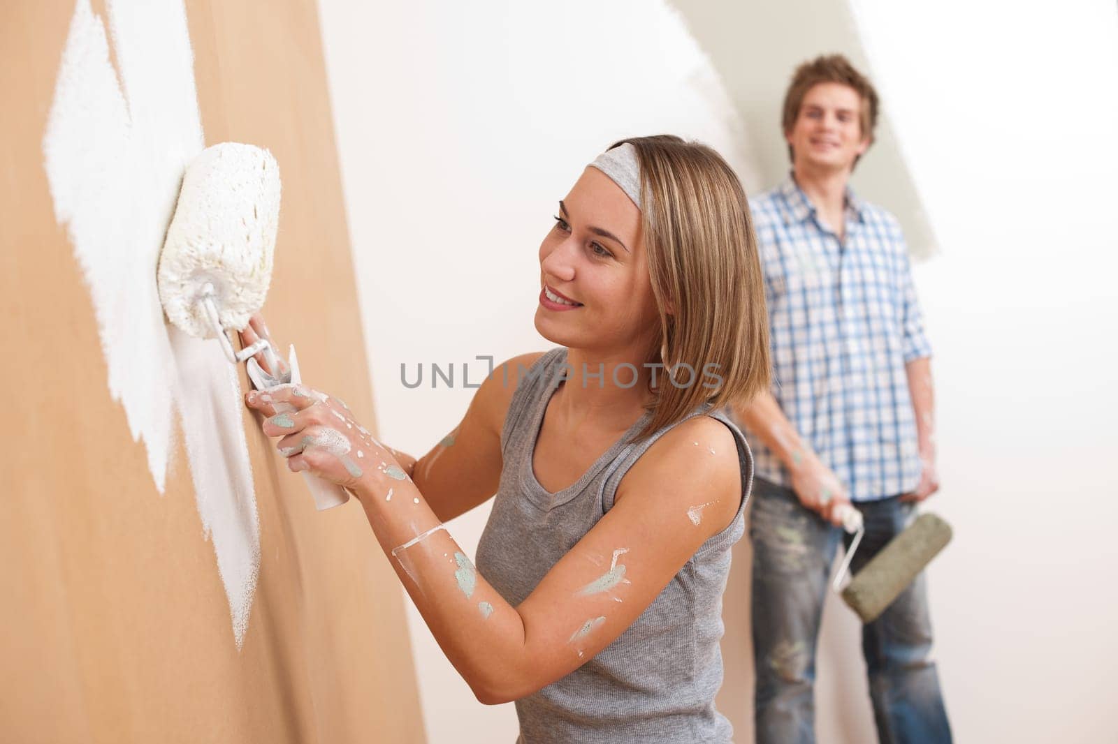 Home improvement: Young man and woman painting wall with paint roller