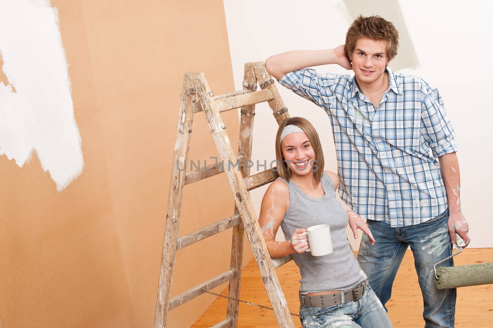 Home improvement: Young couple painting wall with paint roller
