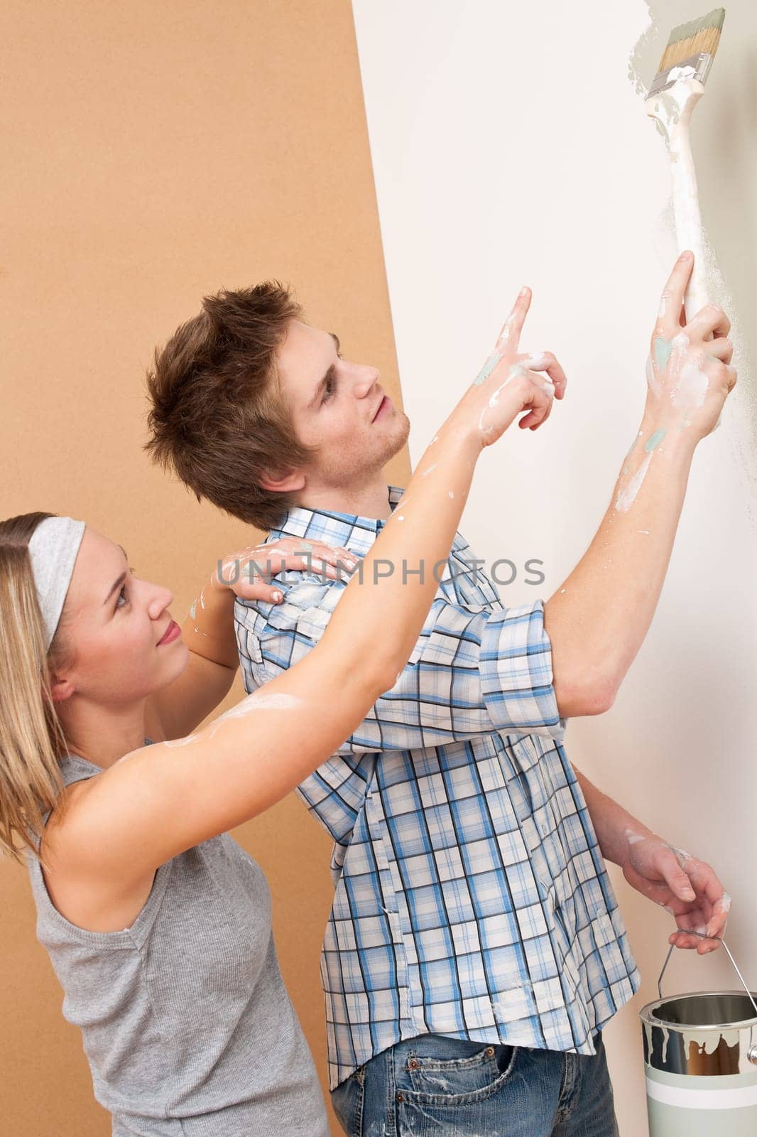 Home improvement: Man painting wall with paintbrush holding paint can