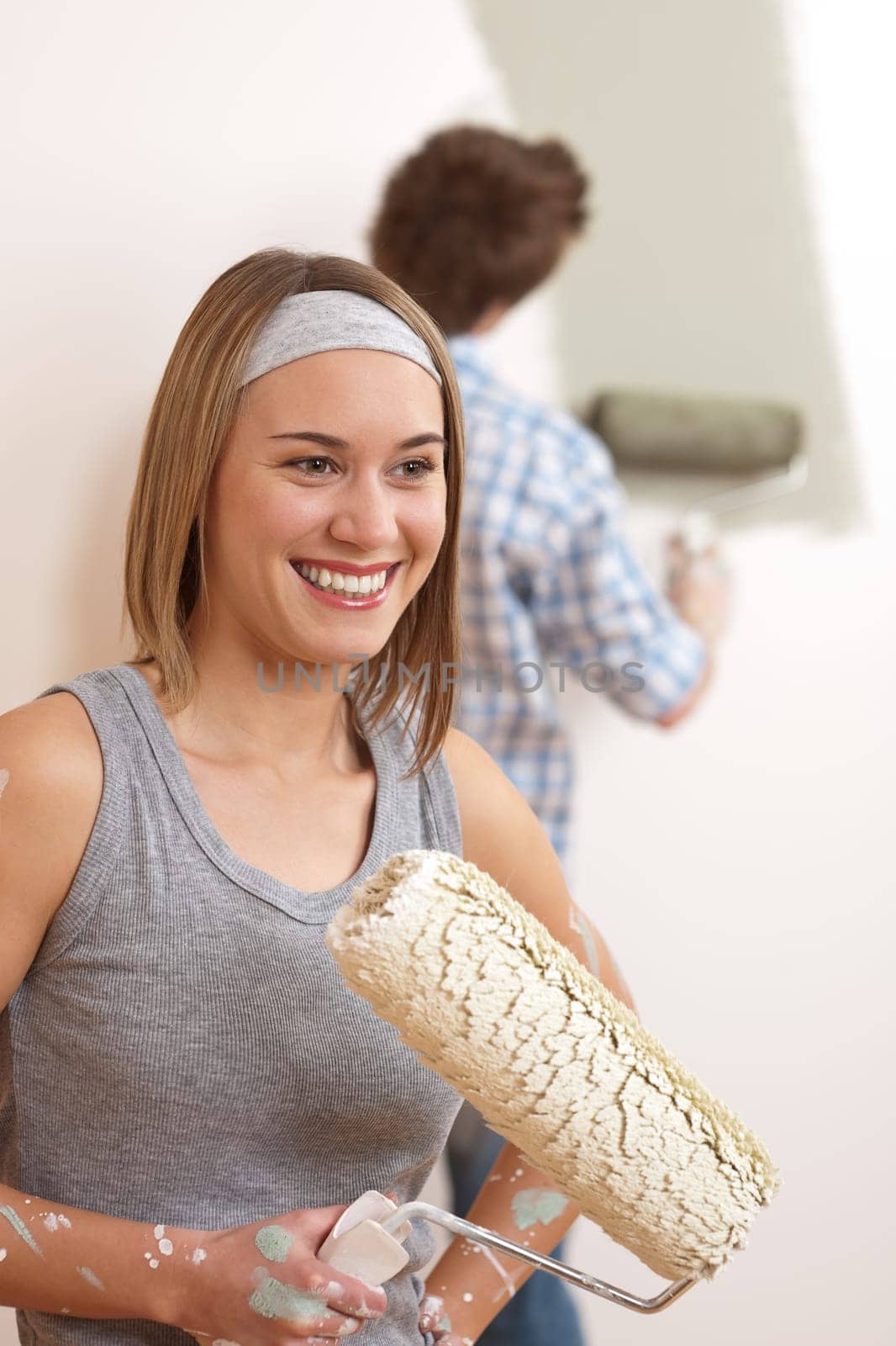Home improvement: Young couple painting wall with paint roller