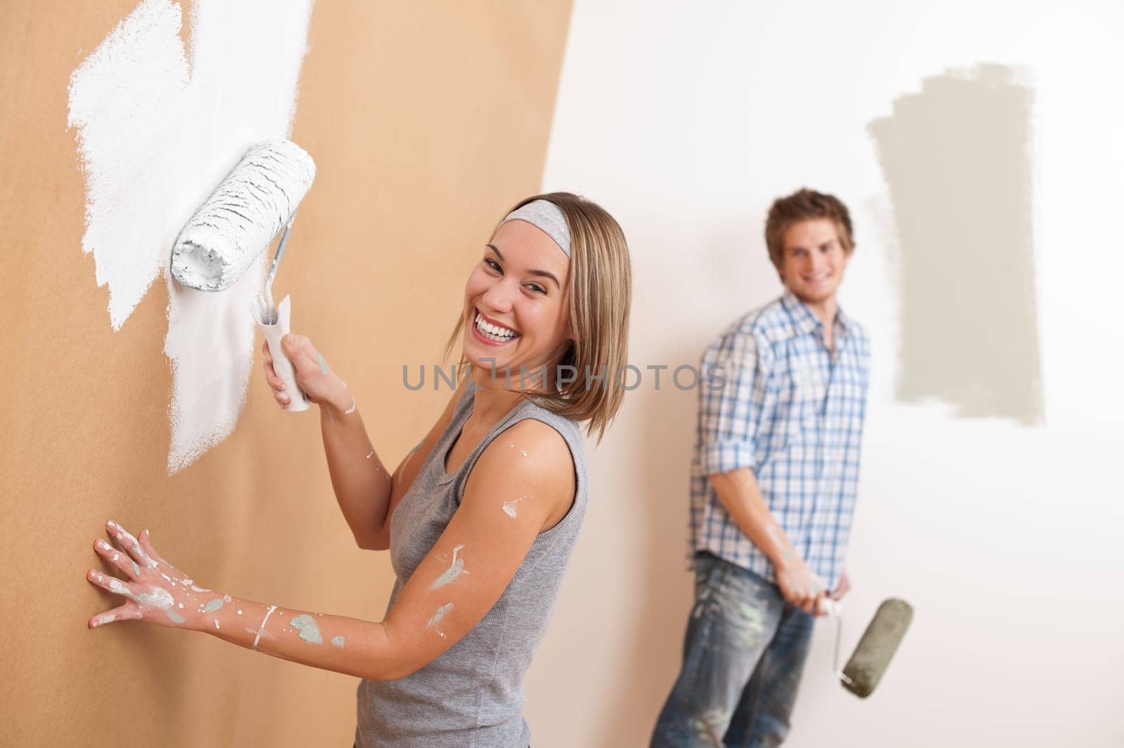 Home improvement: Young couple painting wall with paint roller