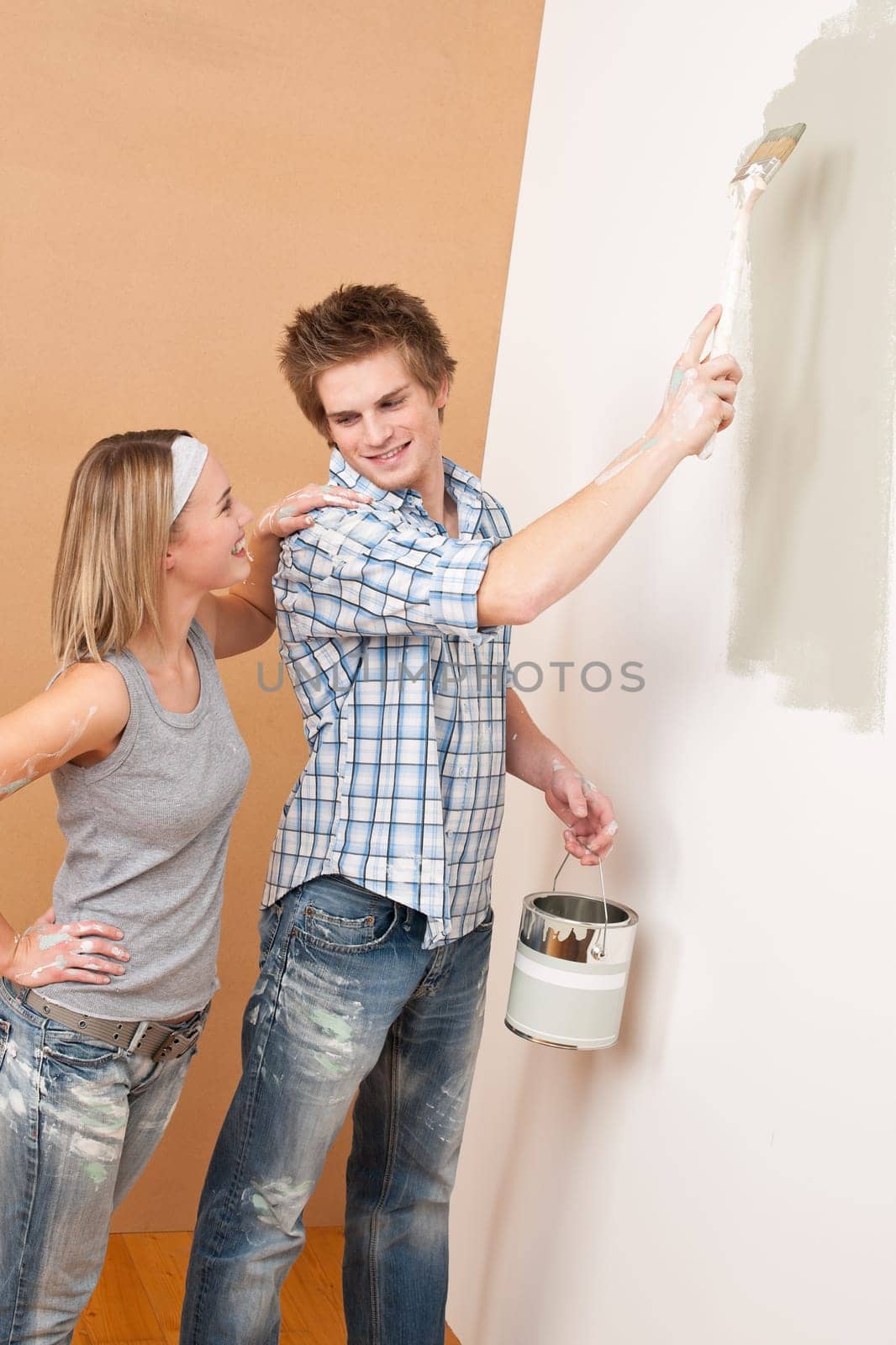 Home improvement: Man painting wall with paintbrush holding paint can