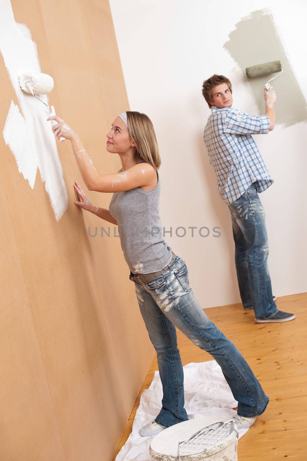 Home improvement: Young couple painting wall with paint roller