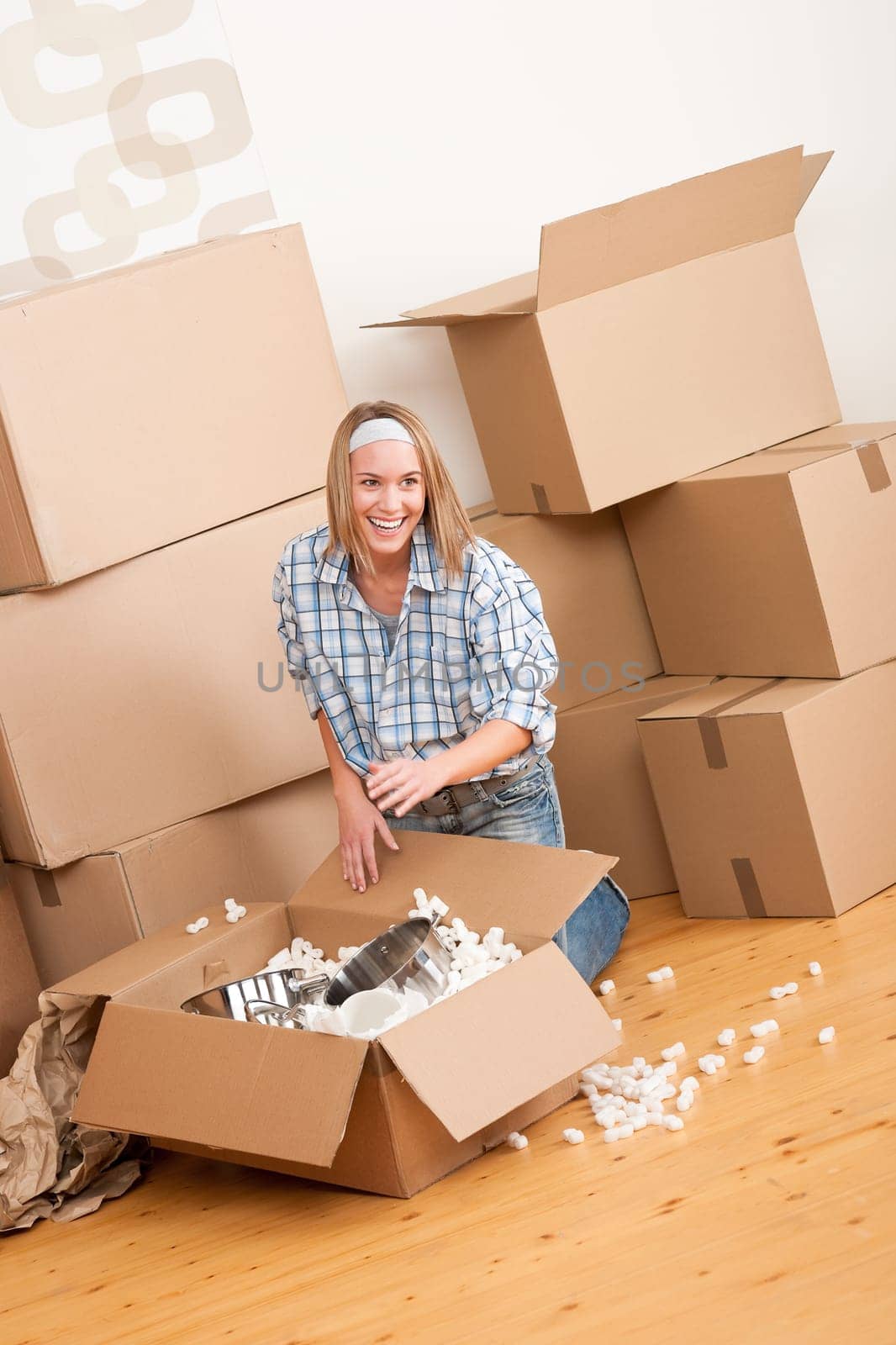 Moving house: Happy woman unpacking box in new home, kitchen, pots and pans