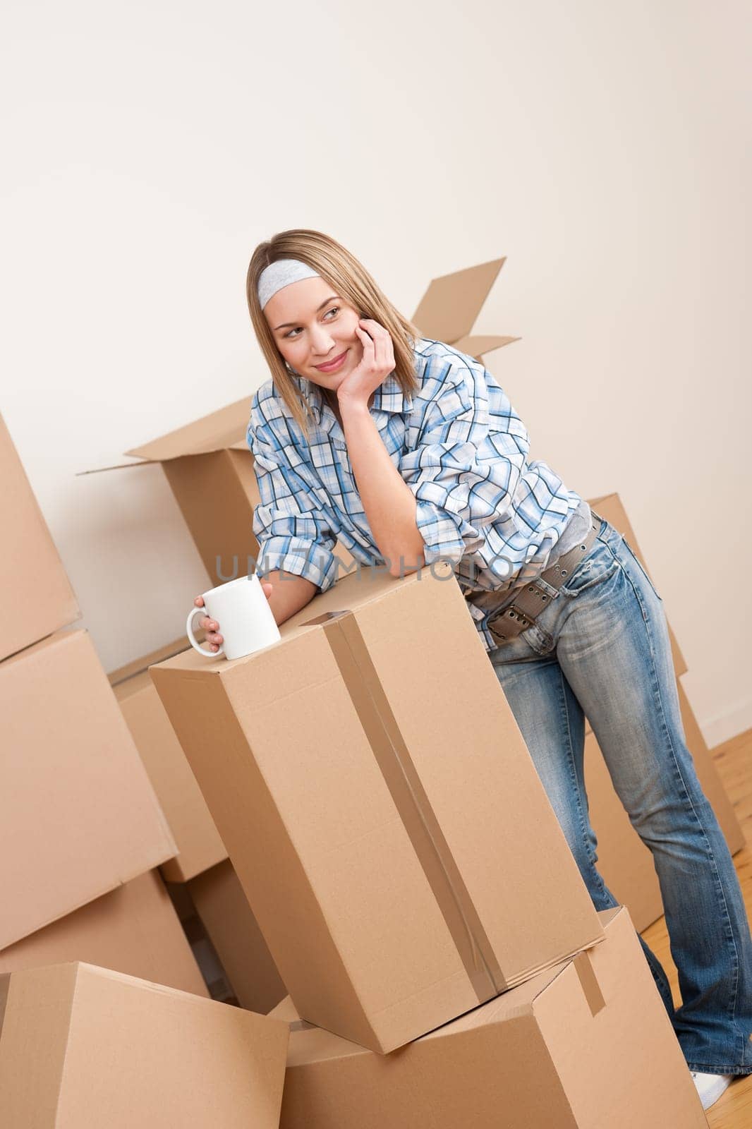 Moving house: Woman with box in new home having cup of coffee