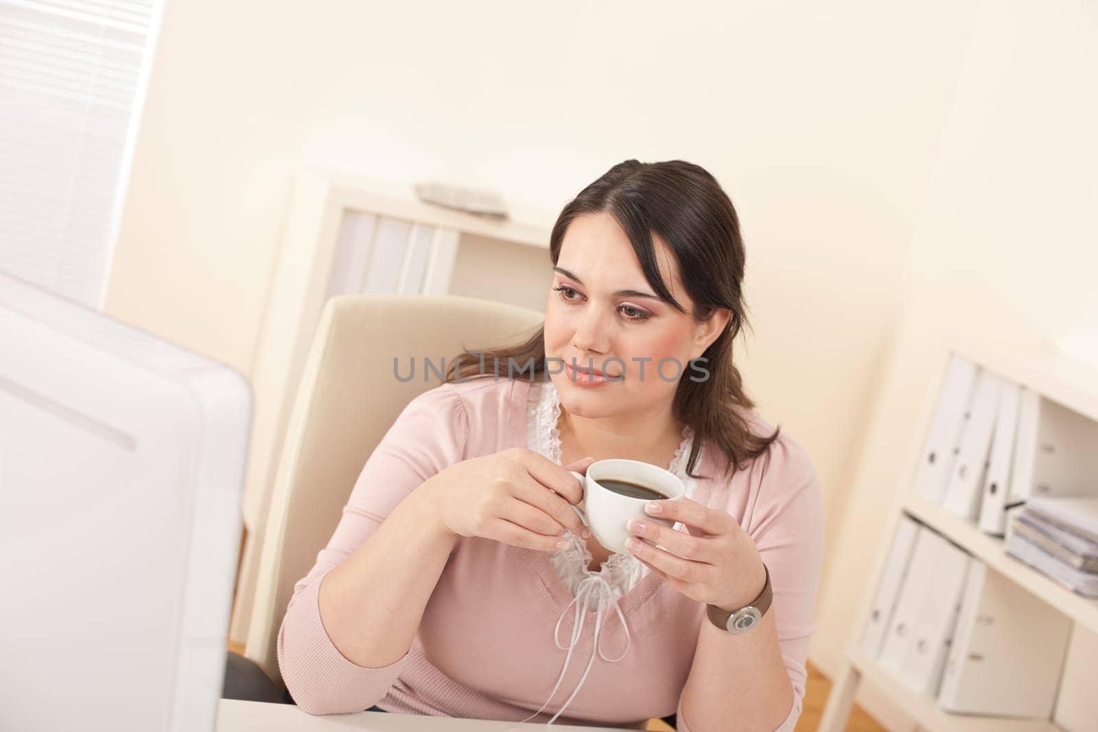 Young business woman enjoying coffee at modern office sitting at computer