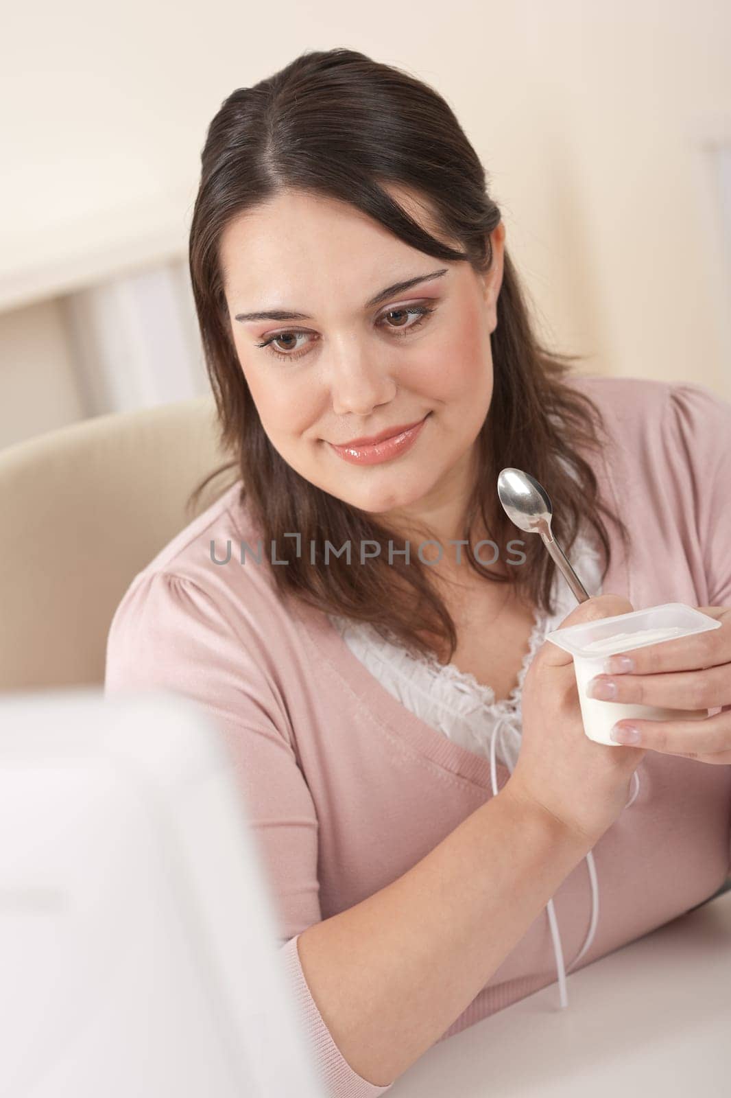 Young businesswoman eating yogurt at office, having break