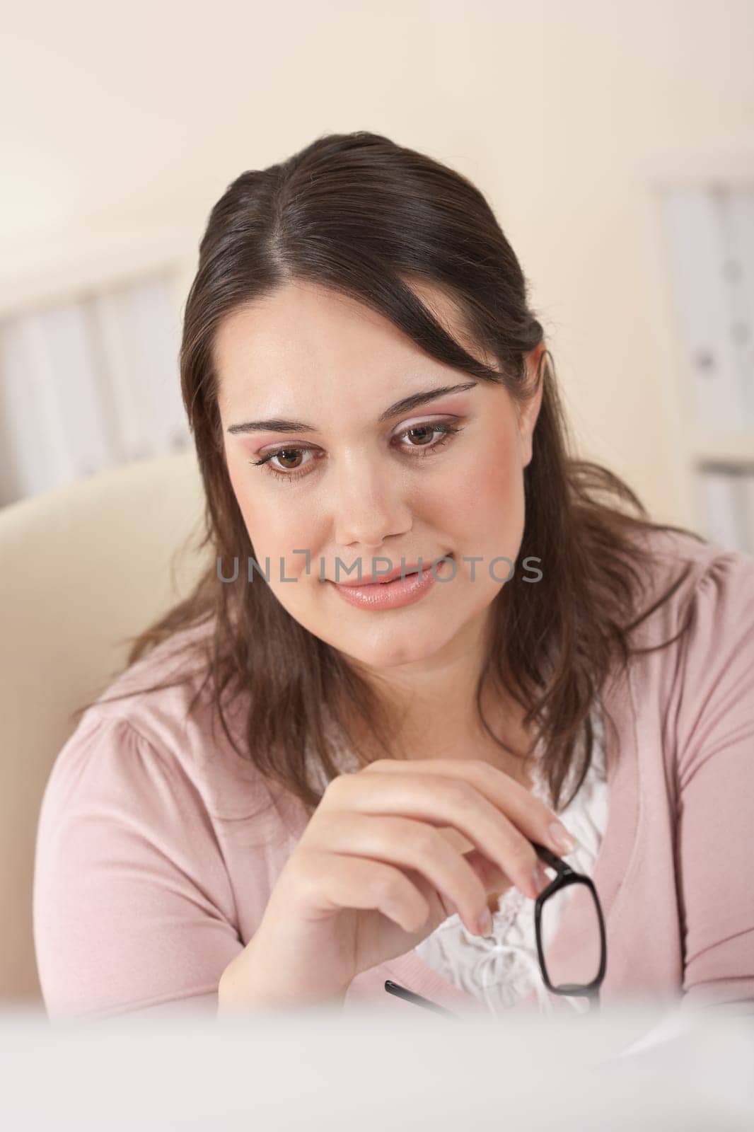 Young businesswoman watching computer screen thinking and holding glasses