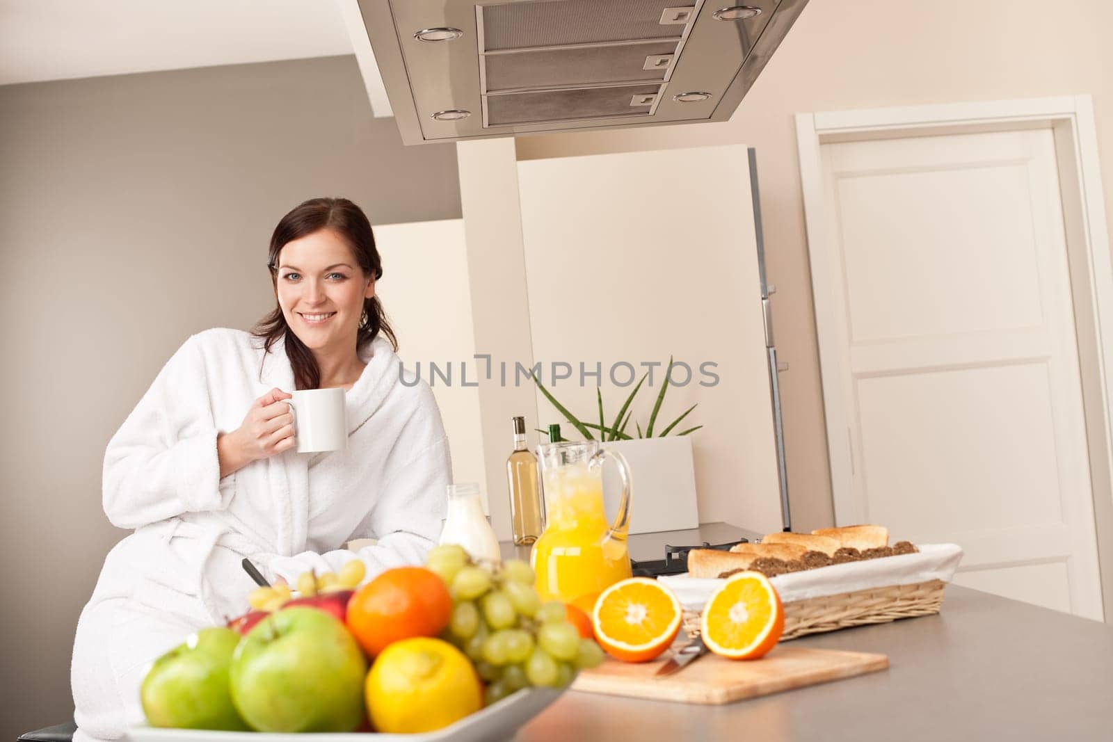 Young woman enjoying coffee and breakfast in modern kitchen